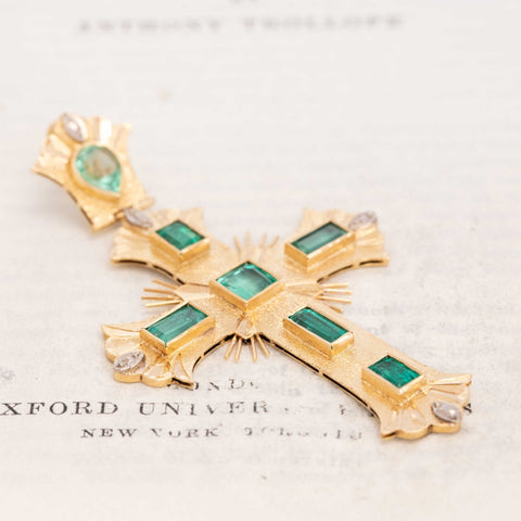 Baroque-style gold cross pendant with emerald gemstones