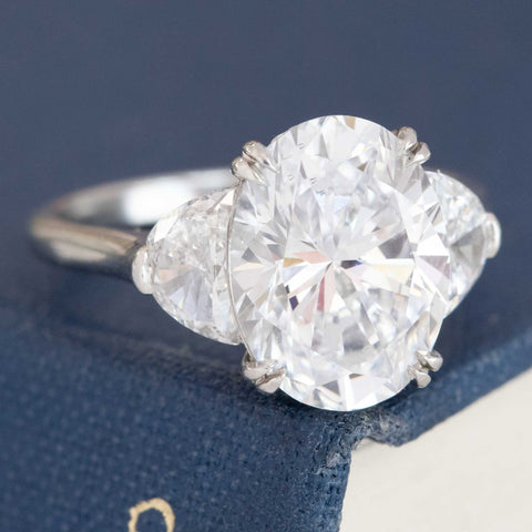 Elegant platinum oval solitaire with half moon diamond shoulders.