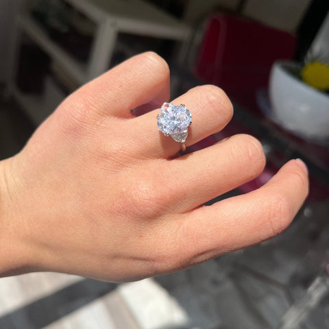 Designer oval diamond ring with hidden halo and icy platinum setting worn on ring finger