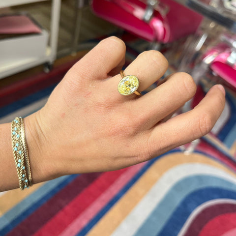 Fancy Yellow Oval Diamond ring with VS2 clarity and rich golden hue shown on ring finger.