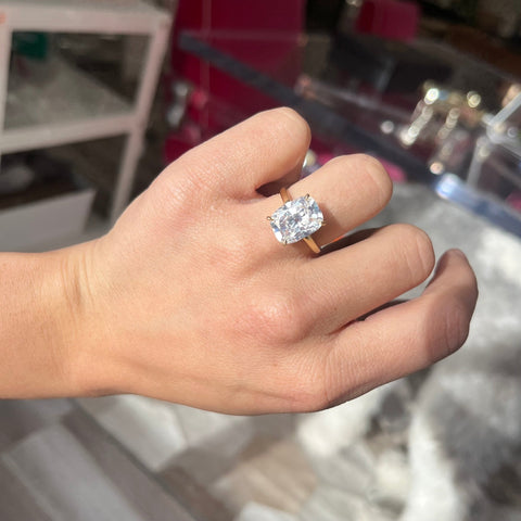 Luxury engagement ring featuring 5ct elongated cushion diamond shown on ring finger