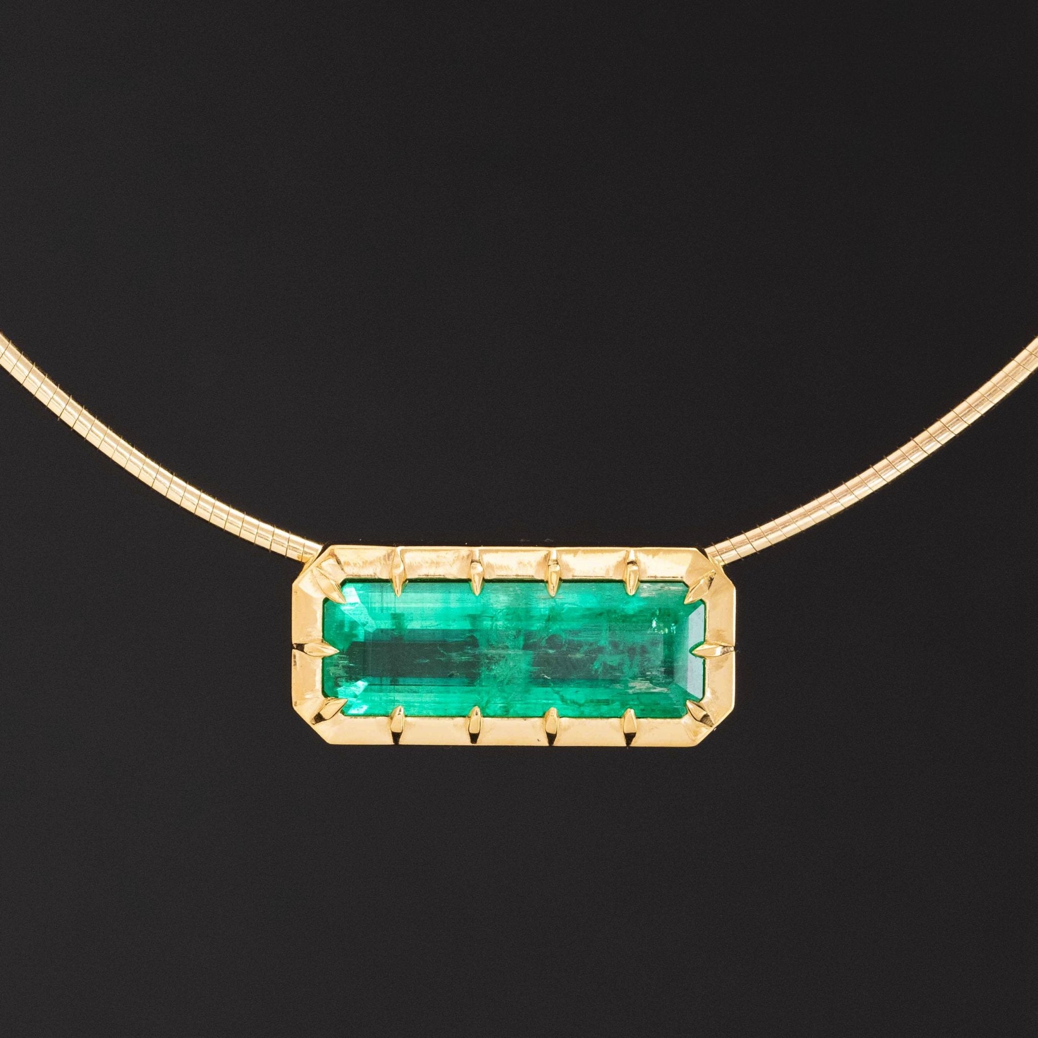 Emerald in gold collet setting on modern gold collar necklace