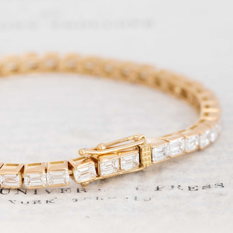 Close-up of emerald cut diamonds bezel-set in yellow gold bracelet