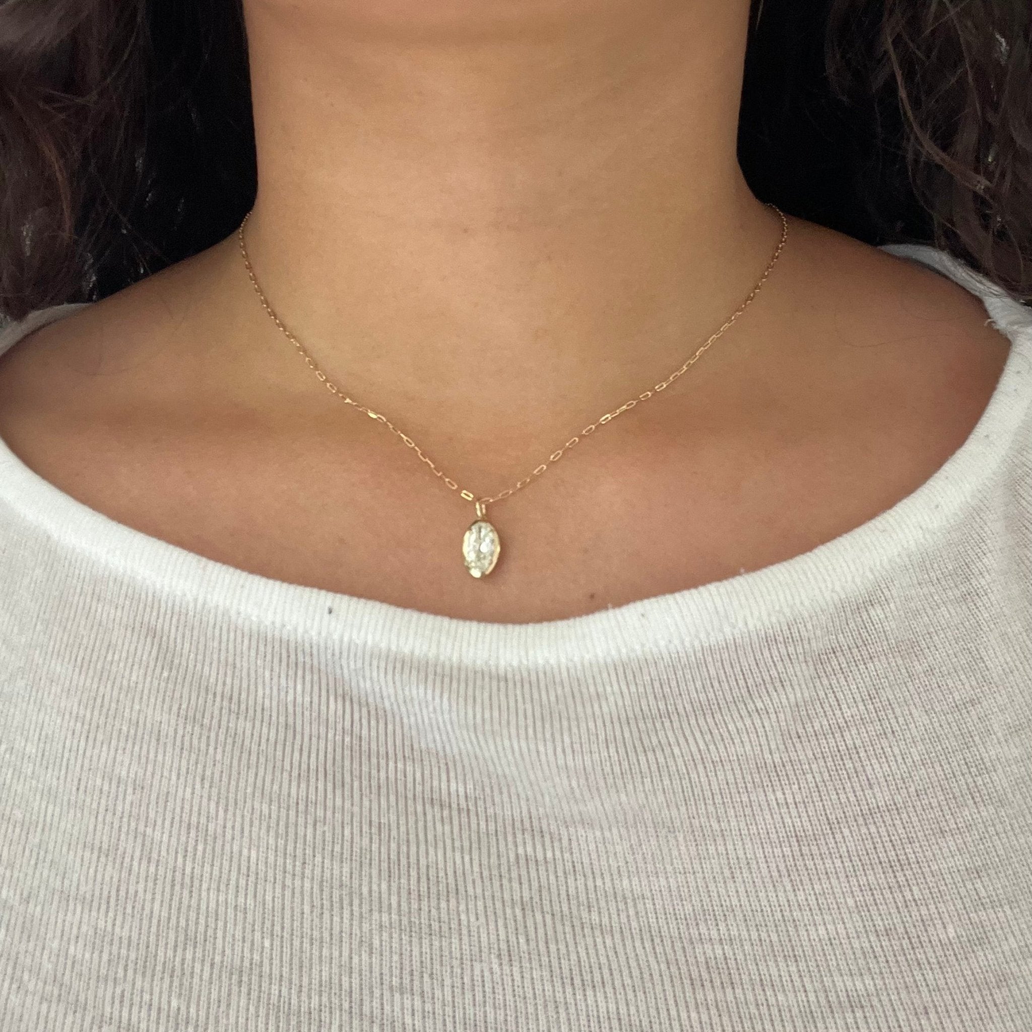 Close-up of marquise diamond pendant in bezel and prong setting, vintage style in yellow gold. Styled on a neck