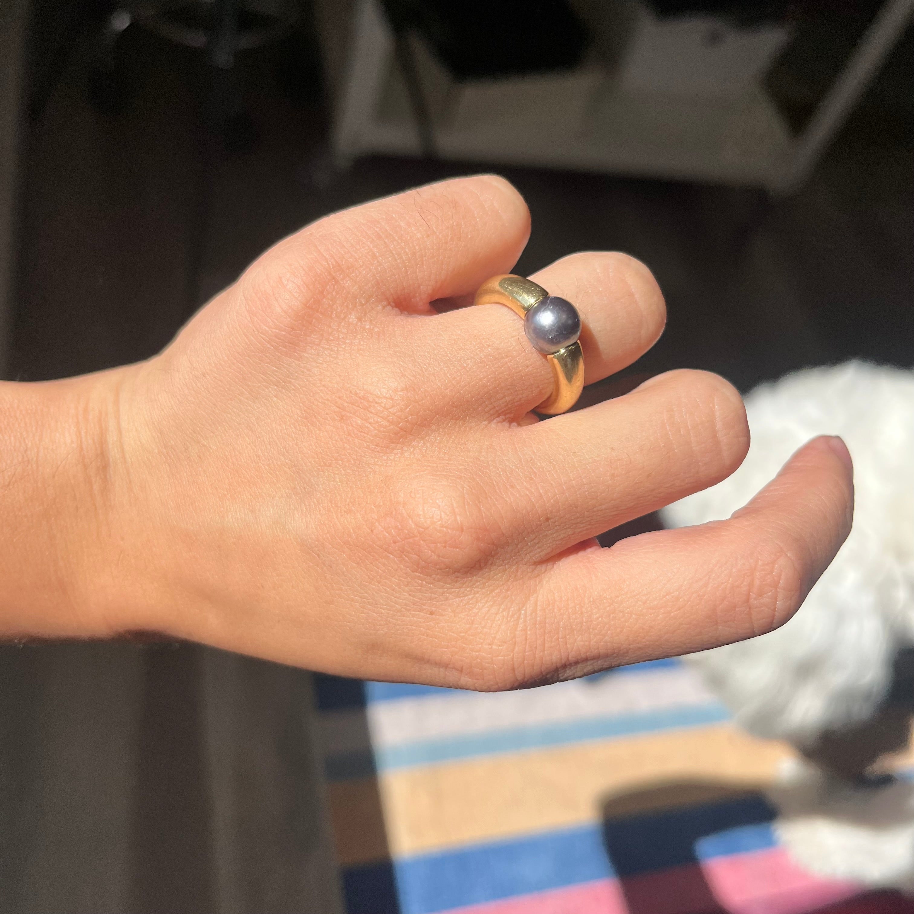 1990s Cartier ring featuring a black pearl tension-set in 18k yellow gold, collectible vintage Cartier jewelry.