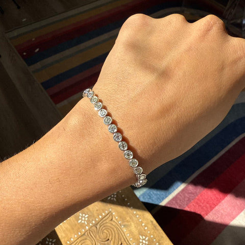 Full view of platinum diamond tennis bracelet on model. Vintage-style diamond tennis bracelet sparkling in natural sunlight