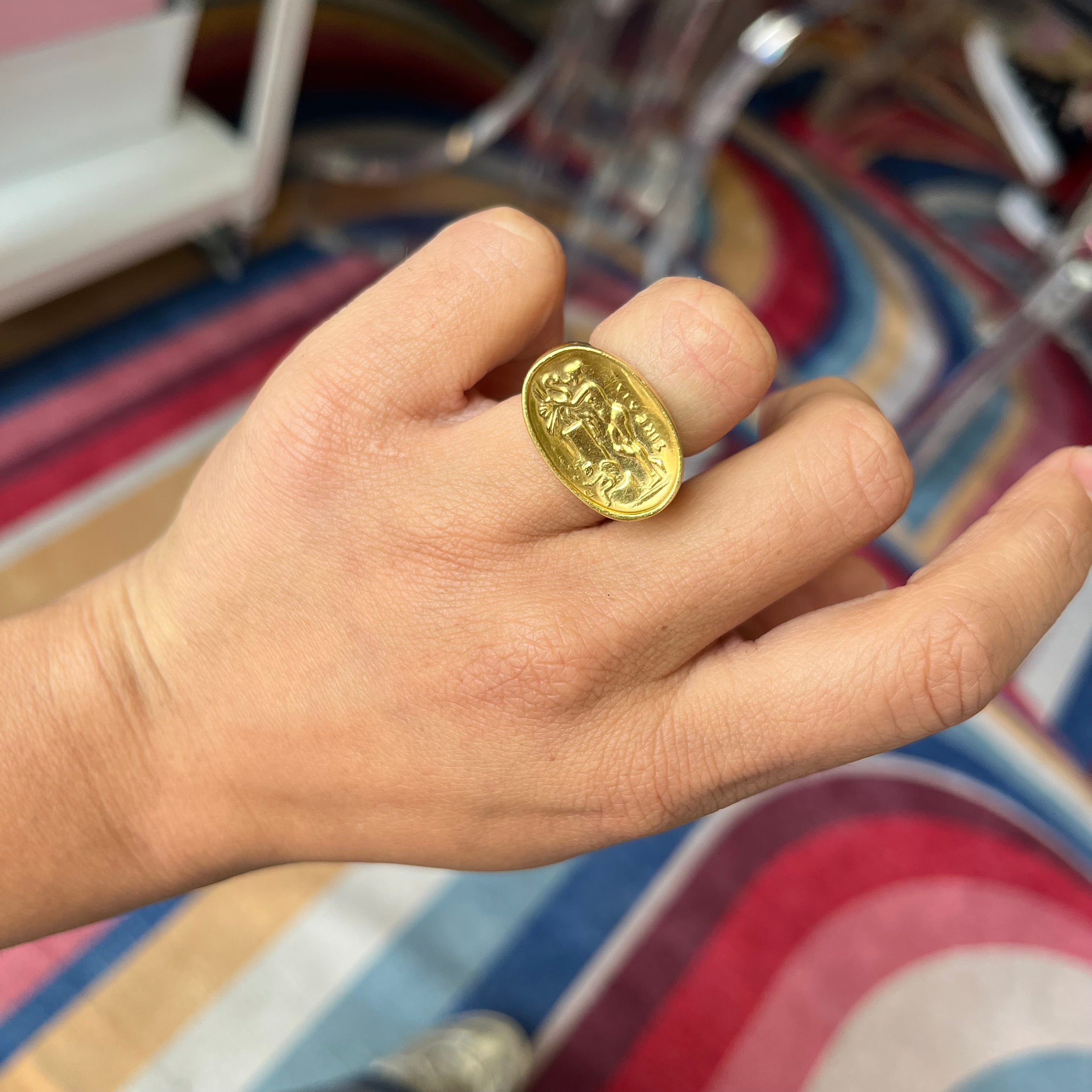 A vintage high karat signet ring  by designer Zolotas depicting "Leda and the swan."  One of a kind and a rare jewel.  Shown on a finger.