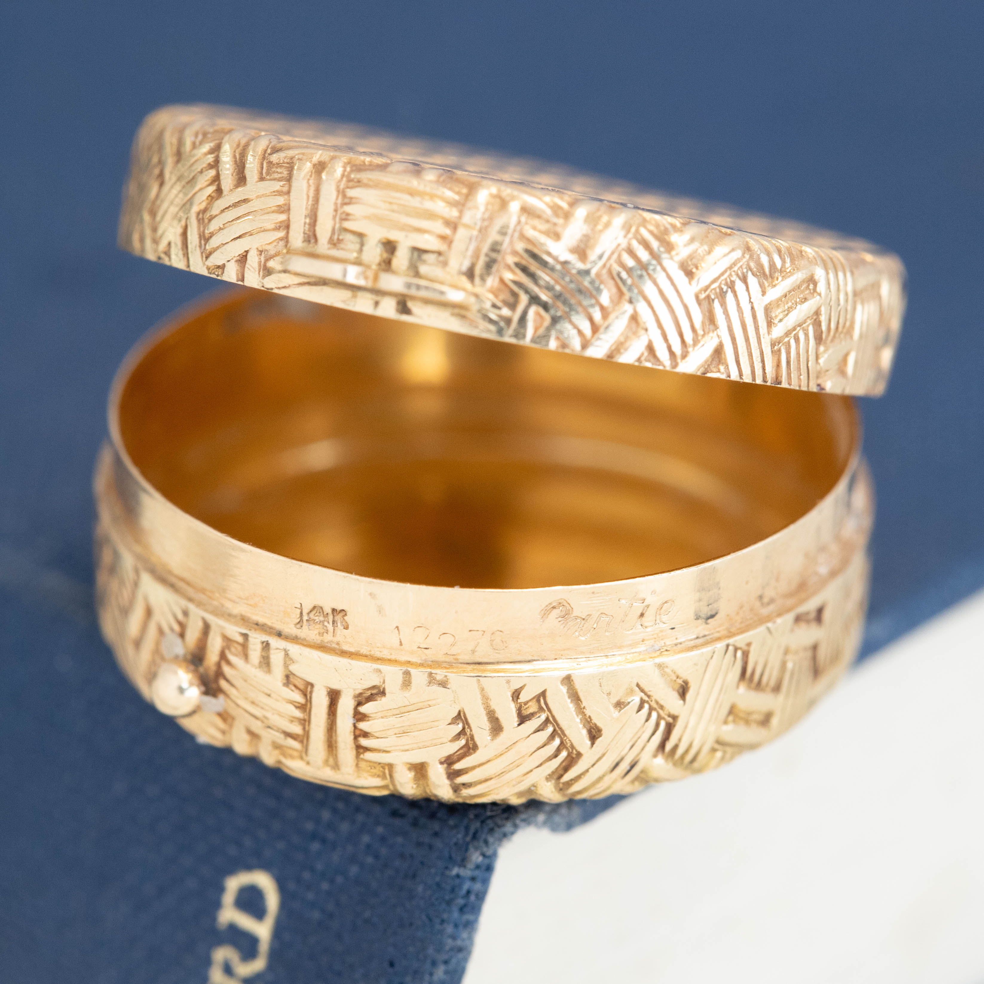 Vintage Cartier 14K yellow gold pill box with hand-engraved basket-weave texture, hinged lid open, showing a polished interior and Cartier signature, with serial 12276.