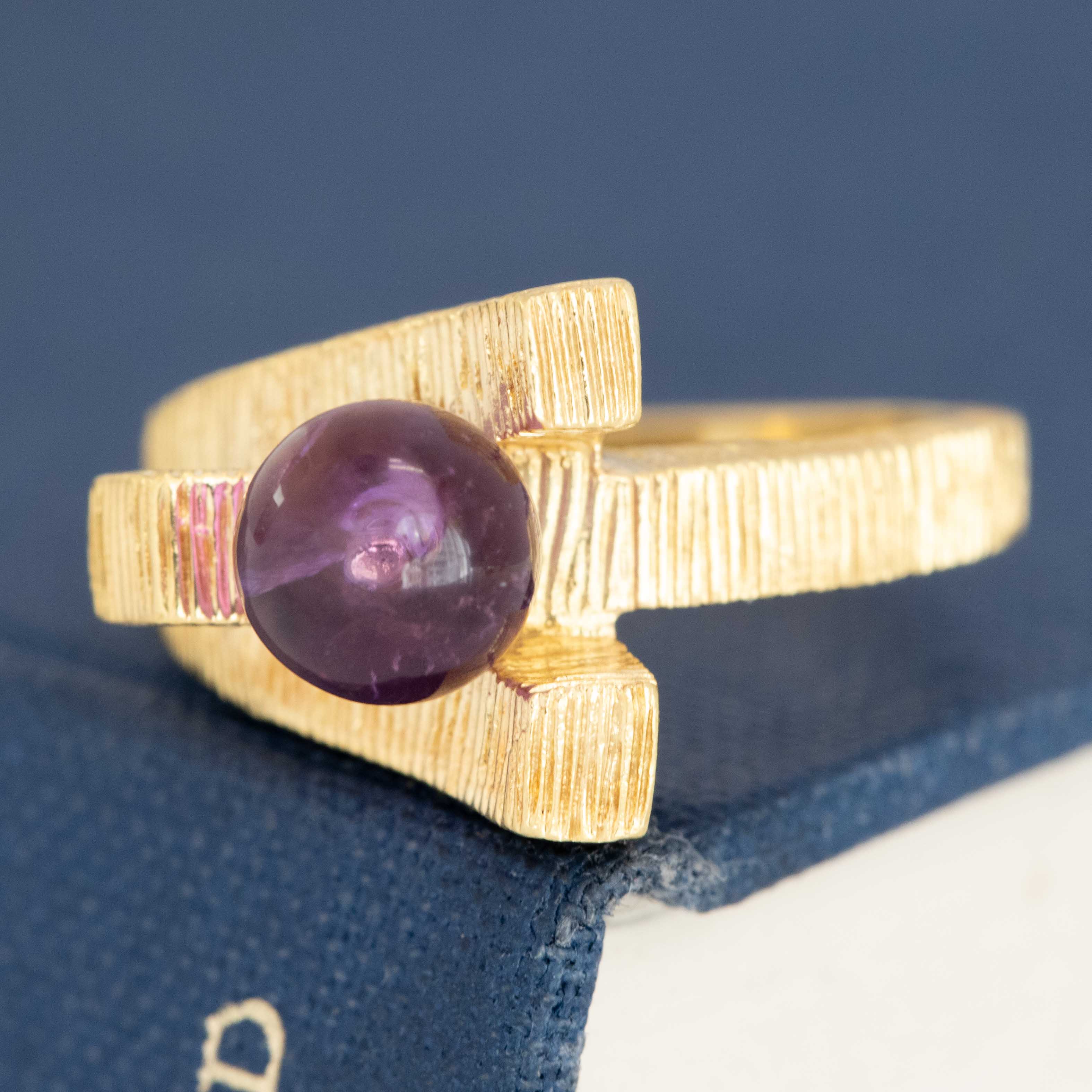 Modernist crossover gold ring featuring round amethyst