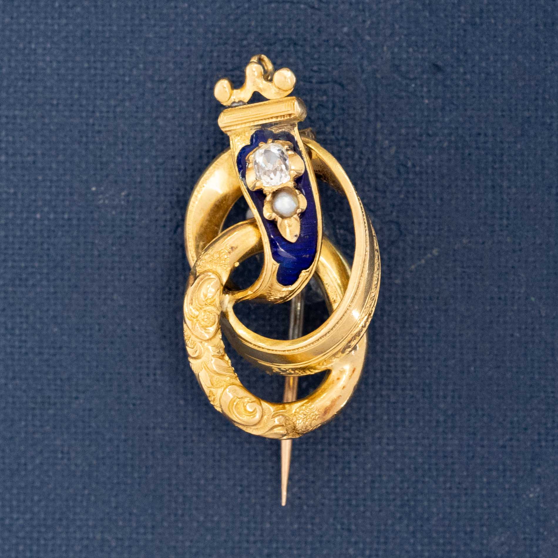 Victorian antique crowned serpent brooch in engraved gold with deep blue enamel, set with a diamond and seed pearl, symbolizing eternal love and triumph.