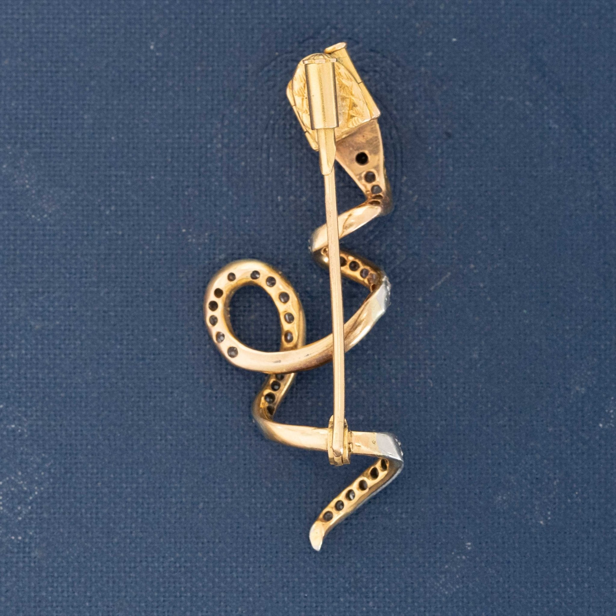 Curled serpent slider-style brooch showcasing pavé diamonds and gemstone accents