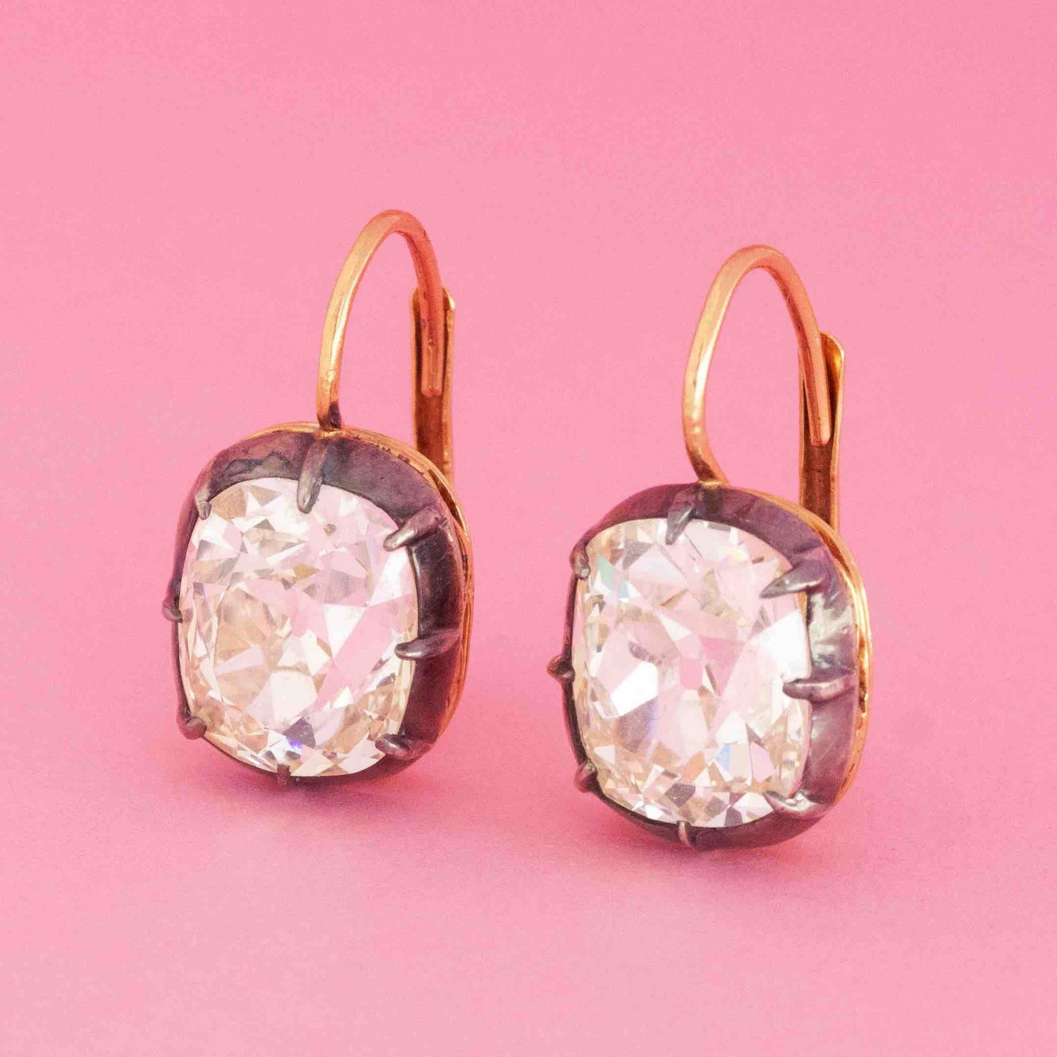 Antique old mine cut diamond collet earrings with 9.16ctw diamonds in silver and 18kt yellow gold on pink background