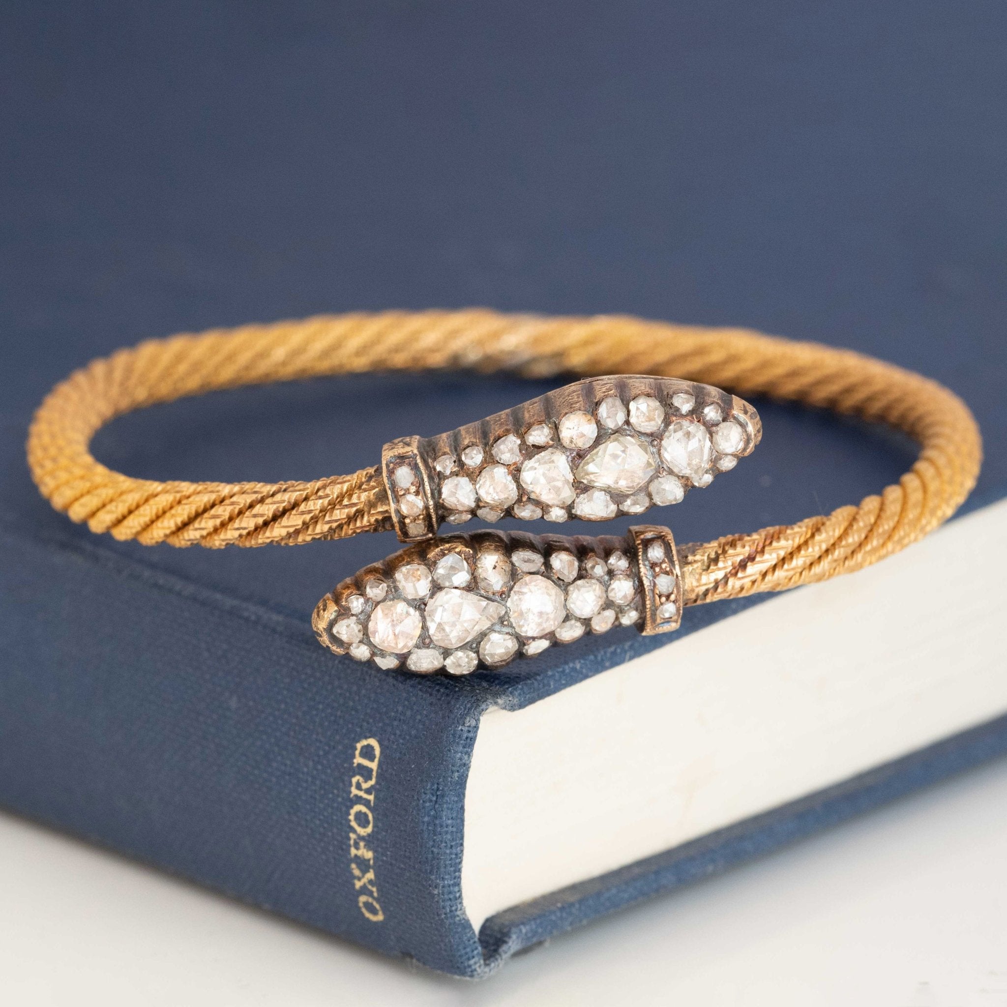 Antique gold serpent bangle with rose-cut diamond serpent heads, a Victorian-era bracelet symbolizing eternal love and wisdom.