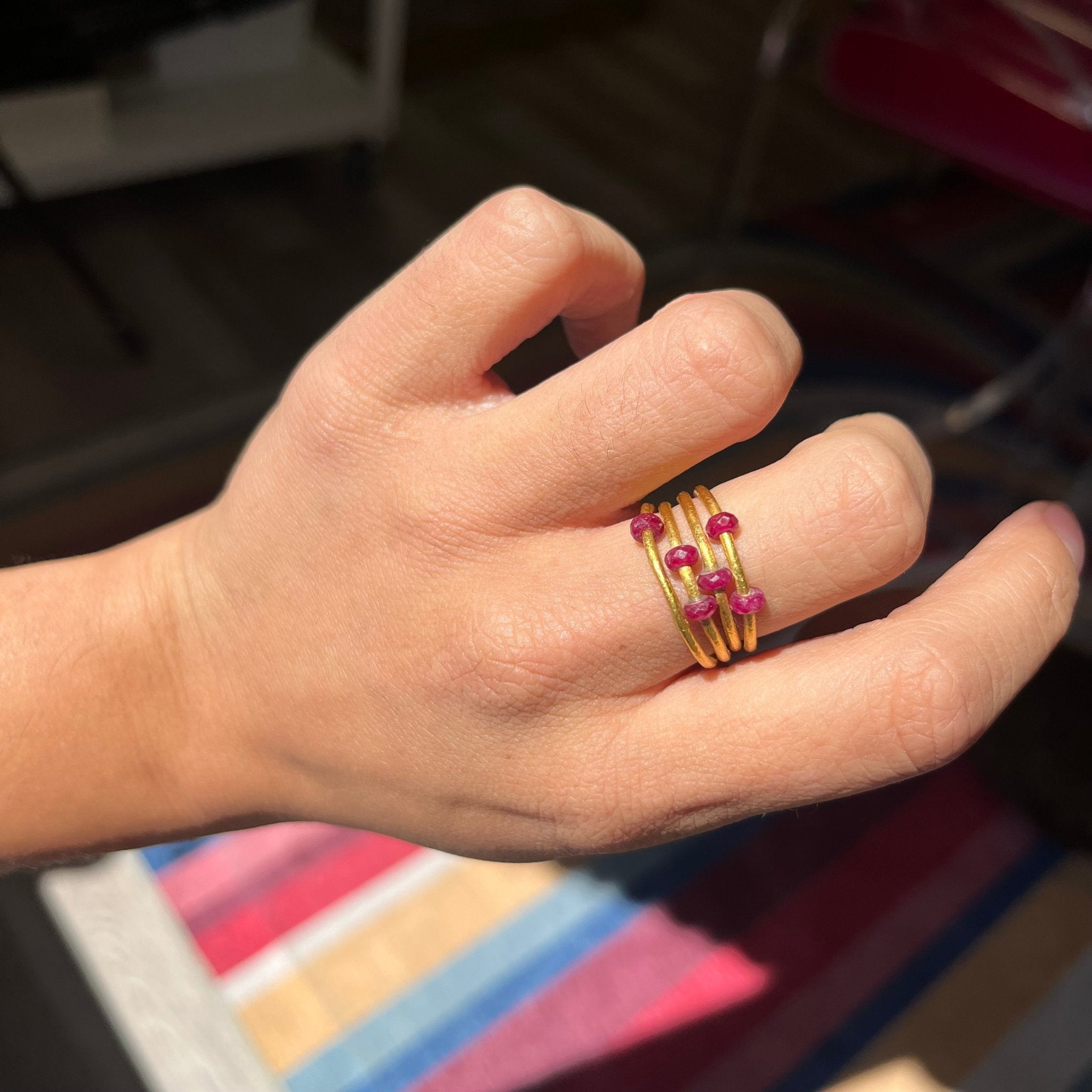 Hand shot of Gurhan coil ring in pure 24k gold featuring natural ruby gemstones – artisan fine jewelry