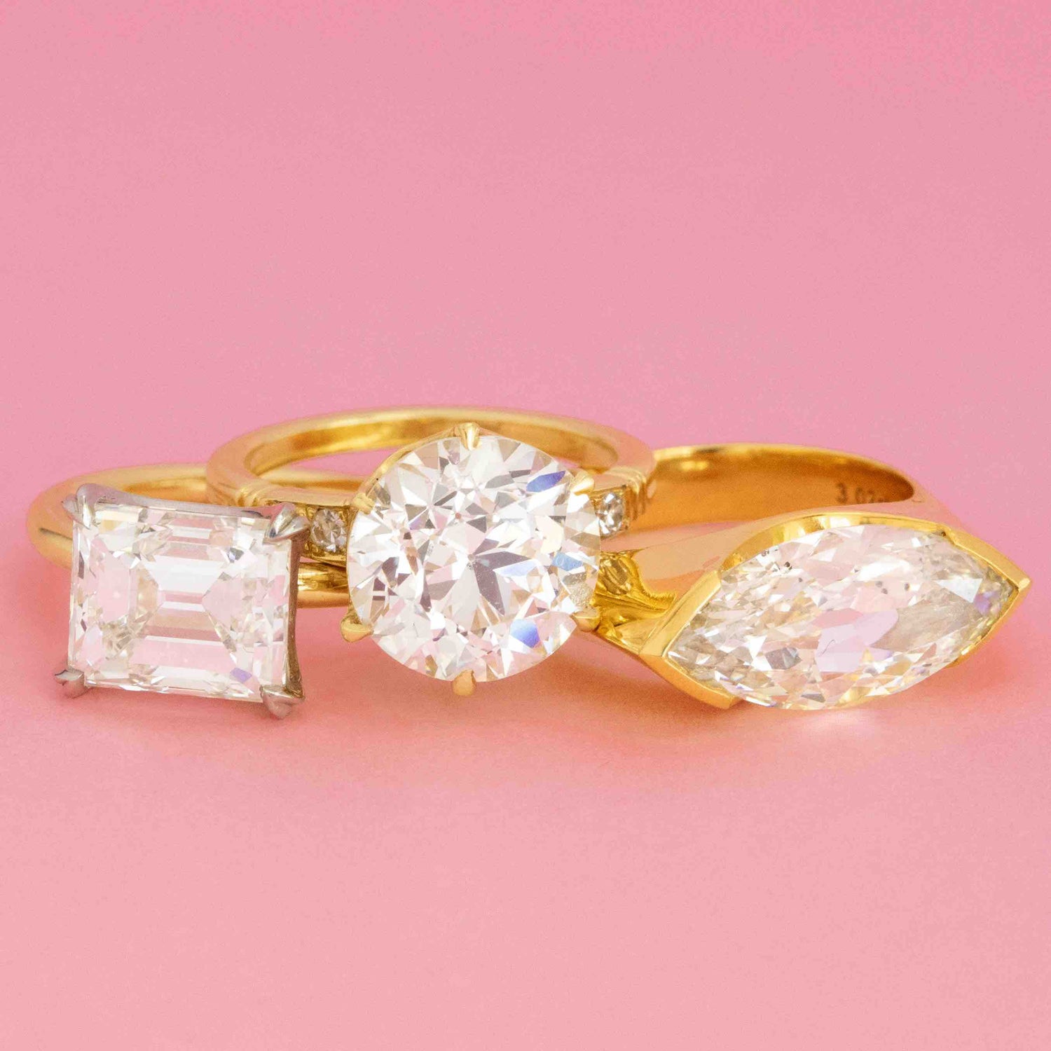 Trio of JbyG engagement rings in yellow gold with antique-cut diamonds in emerald, round, and marquise shapes