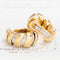 Bulgari two-tone Tubogas gold hoop earrings on neutral background