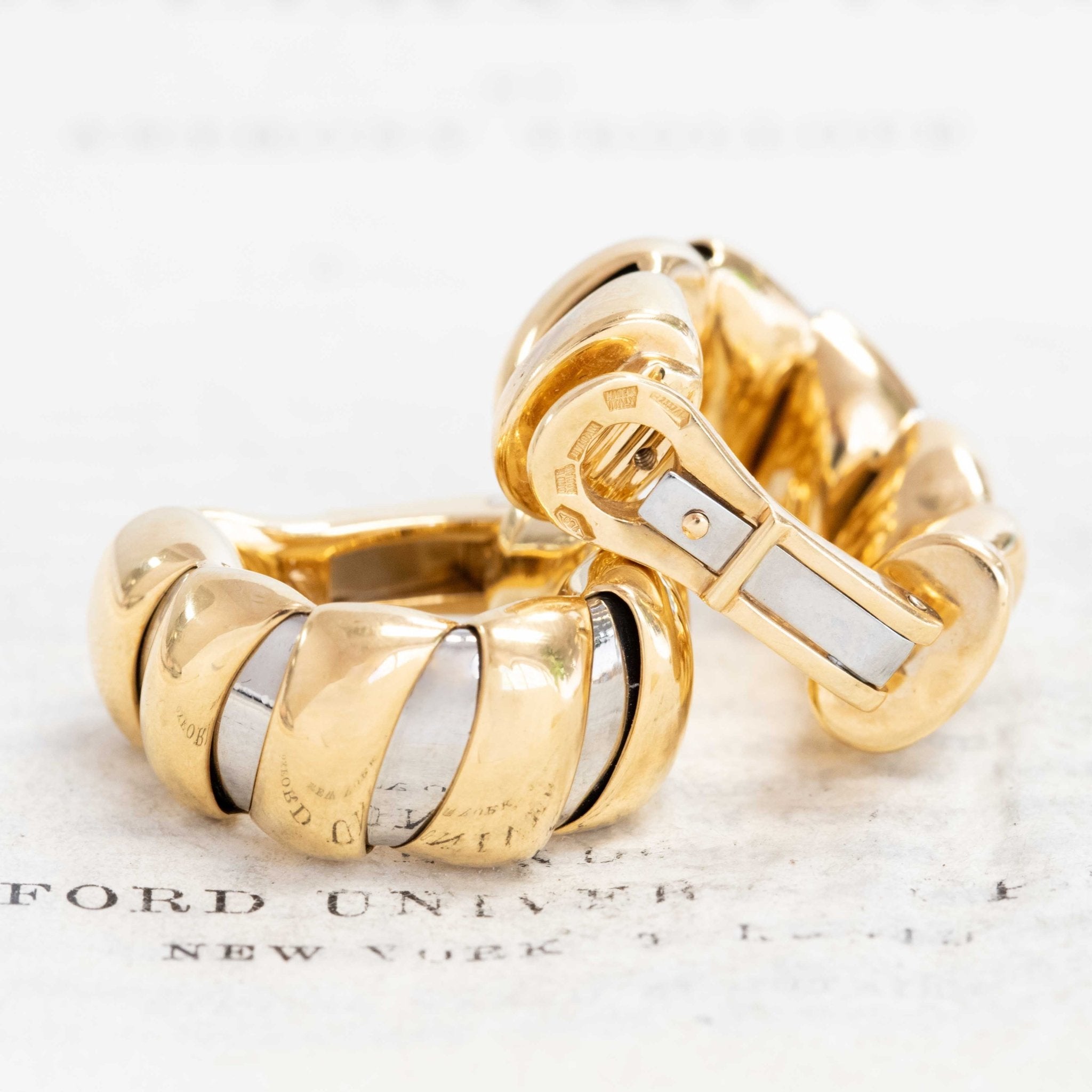 Bulgari two-tone Tubogas gold hoop earrings on neutral background