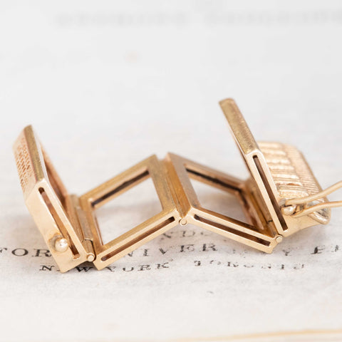 Unique vintage accordion locket charm in yellow gold, hinged design displayed partially open.