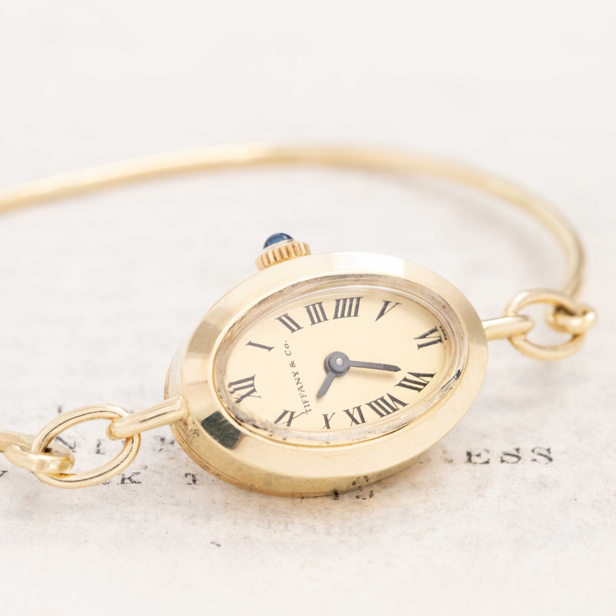 Close-up of Tiffany gold bangle watch on book