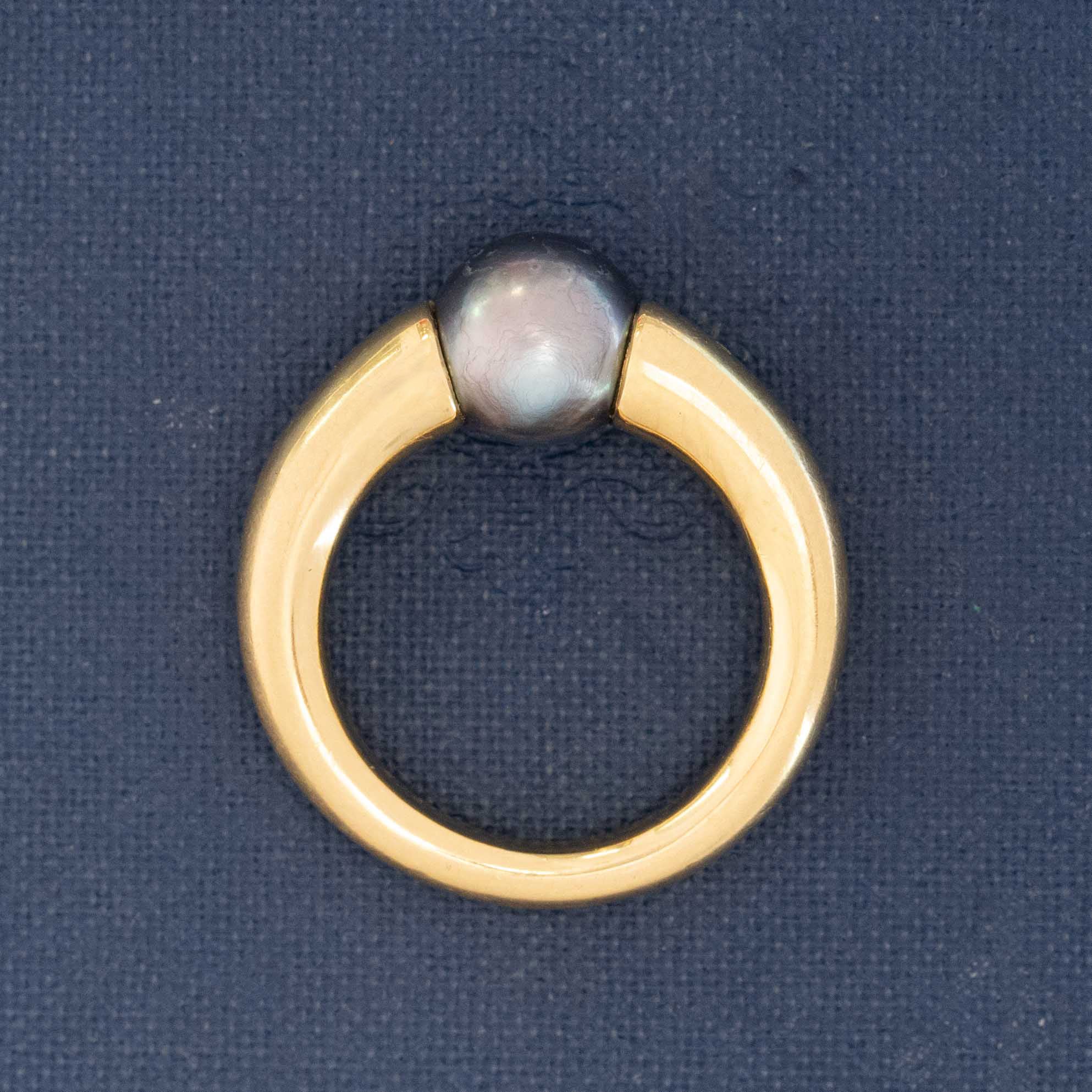 Signed Cartier 90s ring with black pearl in tension setting, crafted in buttery 18k yellow gold.