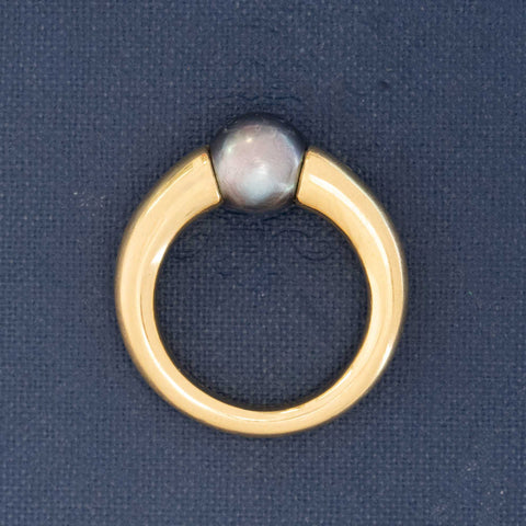 Signed Cartier 90s ring with black pearl in tension setting, crafted in buttery 18k yellow gold.