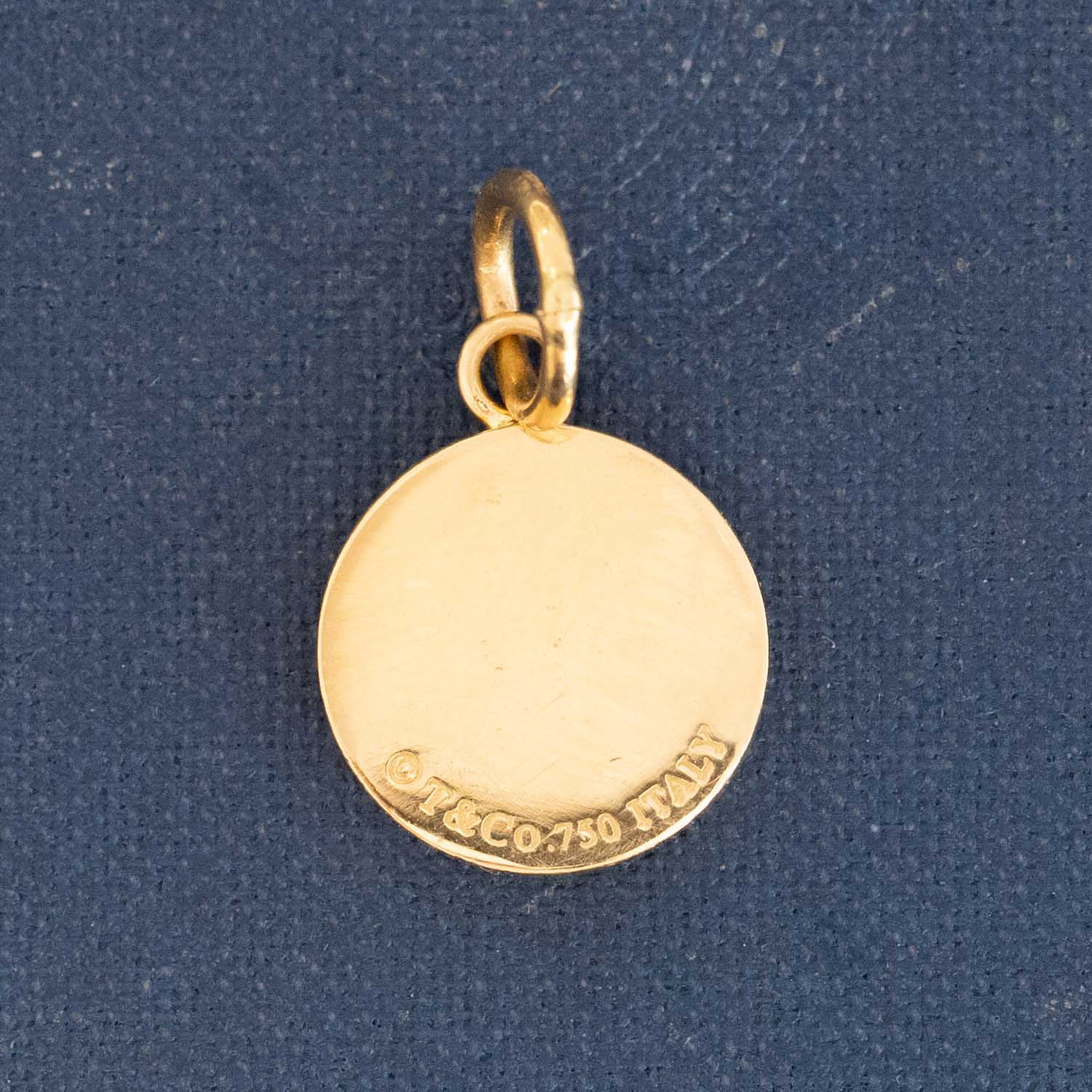 Close-up of Tiffany &amp; Co. yellow gold charm pendant stamped 1837 with diamond accents.