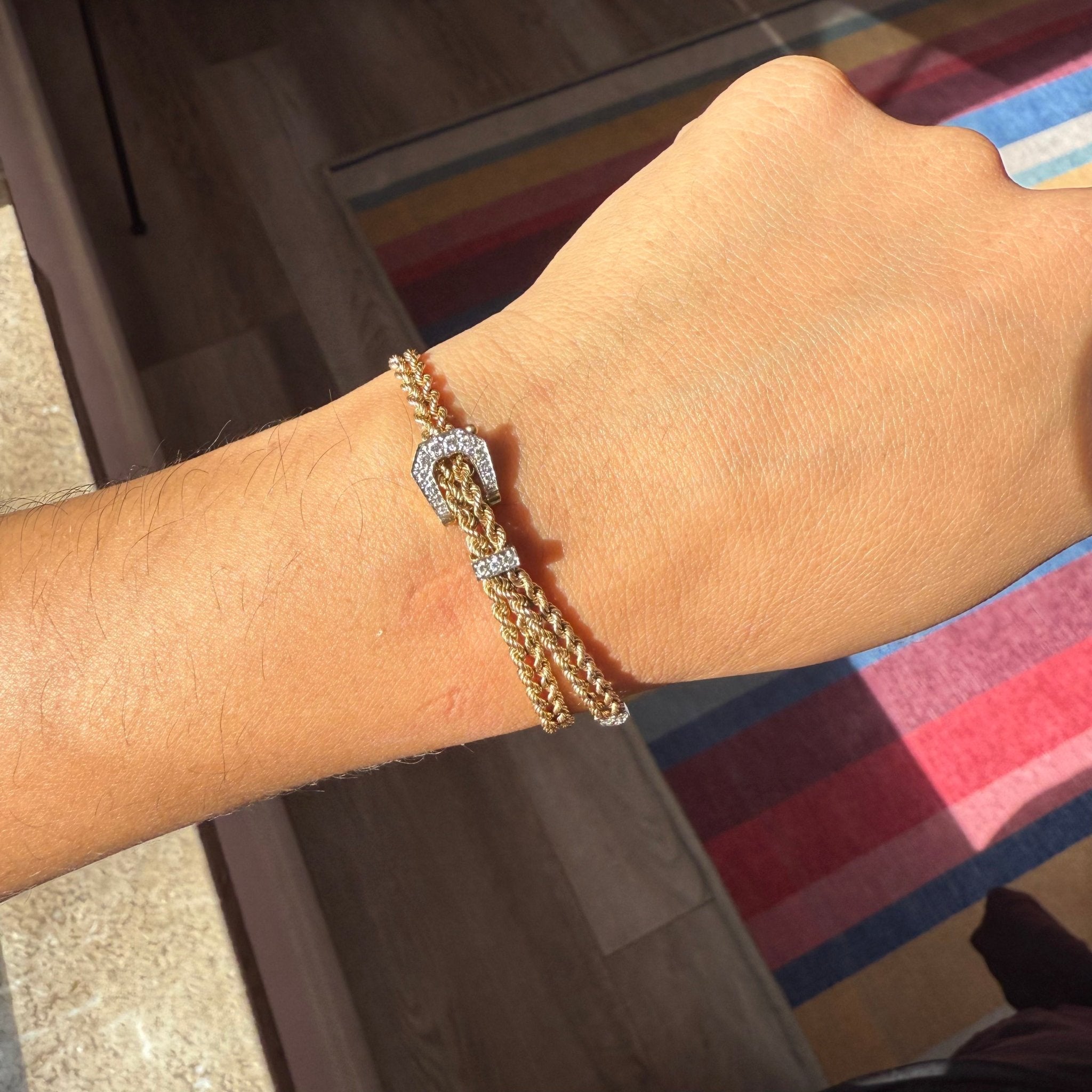 Gold buckle bracelet on a wrist with a blurred background