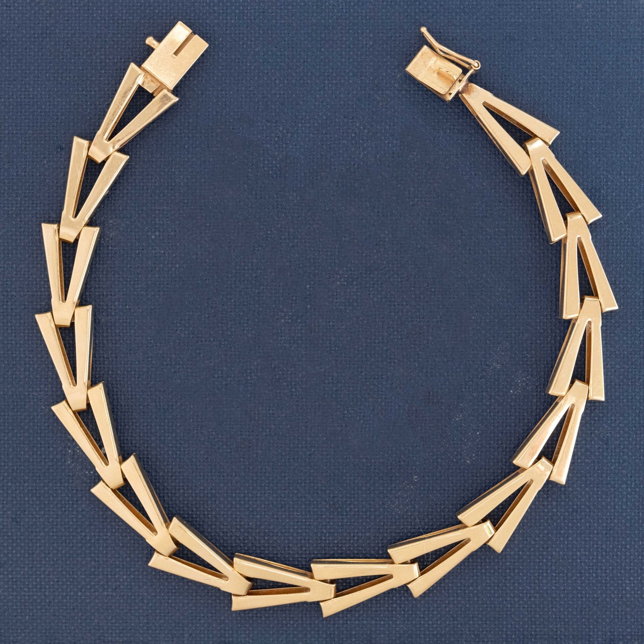 14kt yellow gold V-link bracelet with geometric design displayed on navy background.