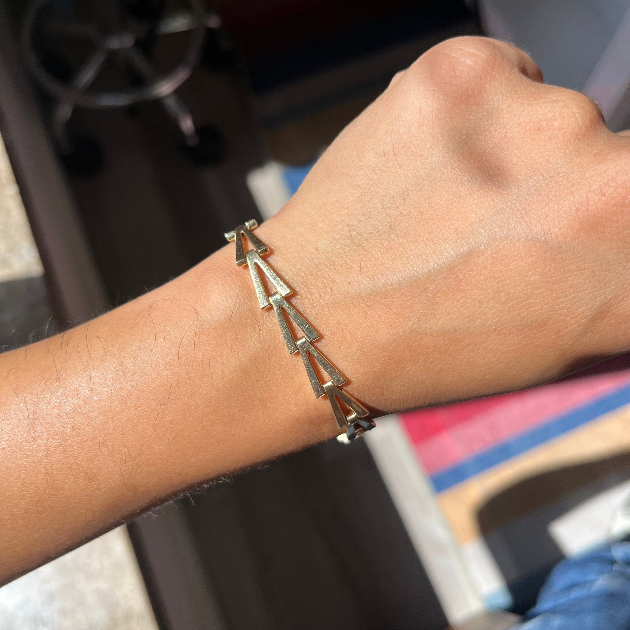 Elegant yellow gold link bracelet with bold geometric pattern shown on te wrist