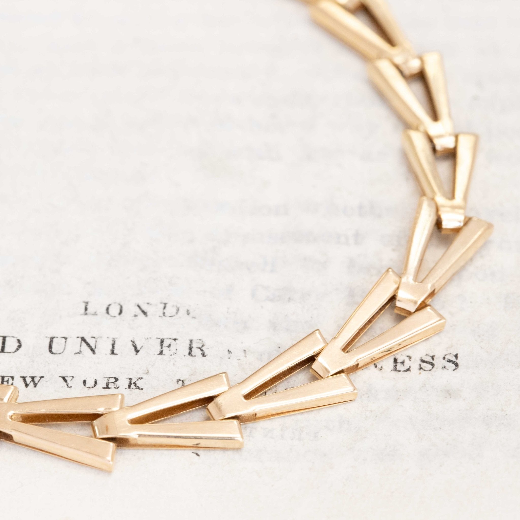 Close-up of modern gold bracelet featuring interlocking V-shaped links.