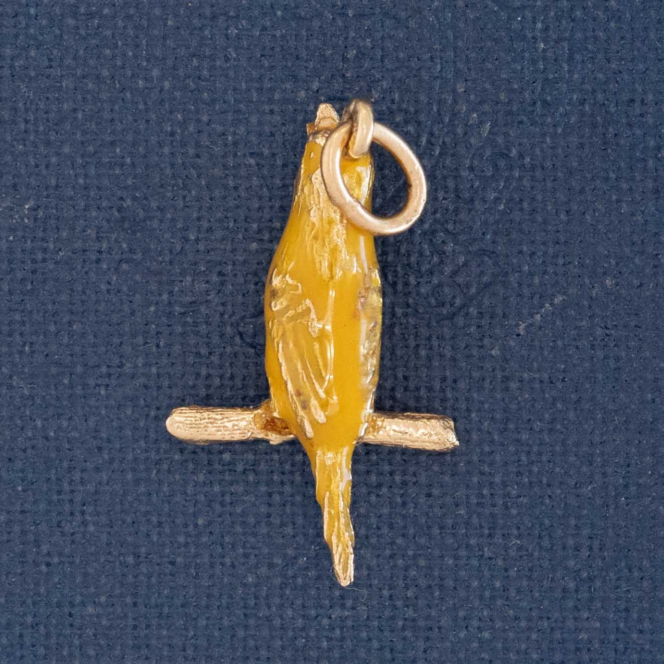Vintage gold and enamel canary charm with yellow enamel bird perched on branch.