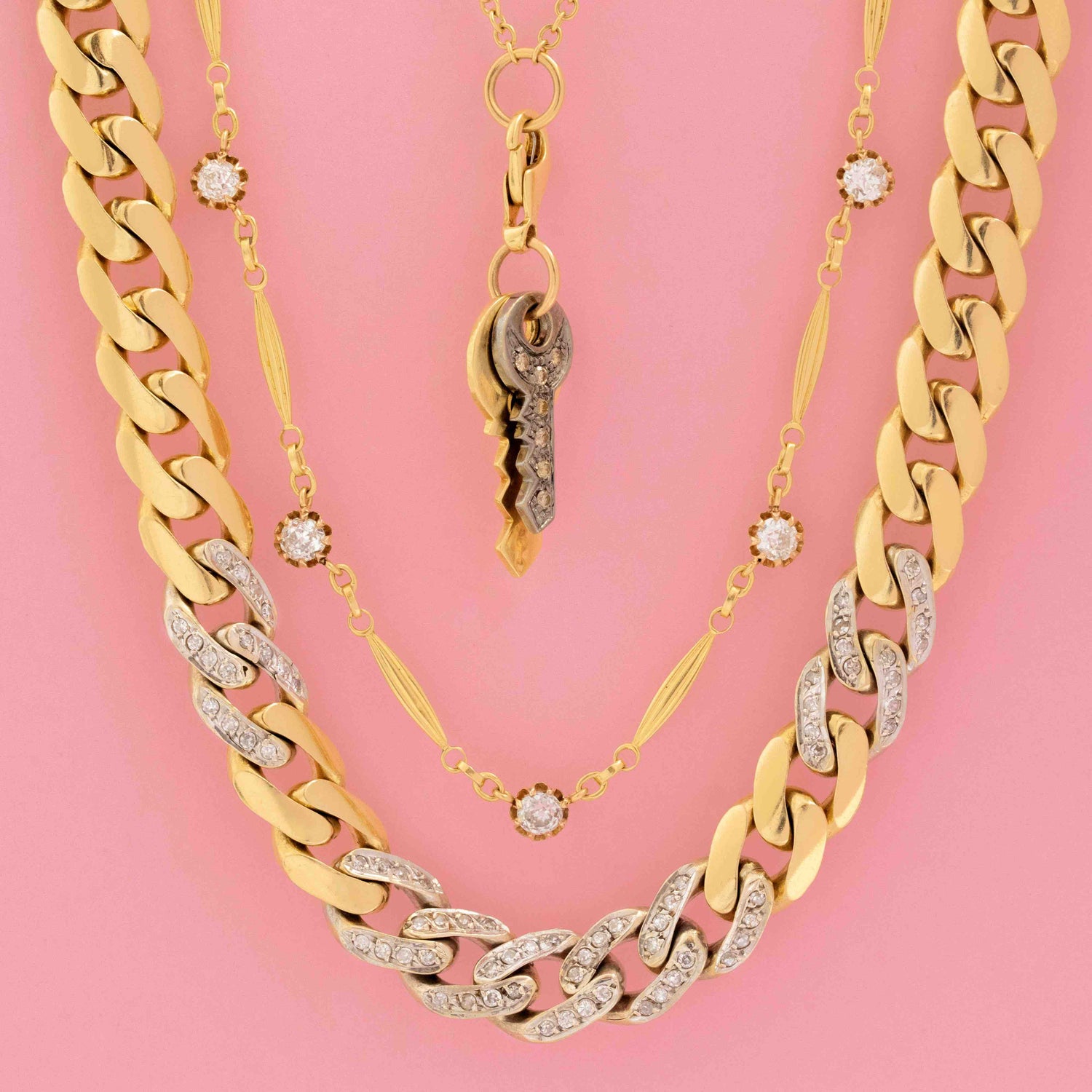 Layered vintage gold necklaces featuring diamond pavé curb chains, antique key pendant, and diamond station necklace