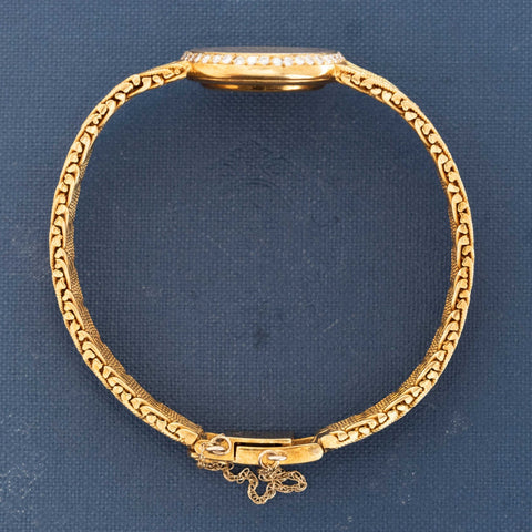 Gold bracelet with intricate design on a blue background