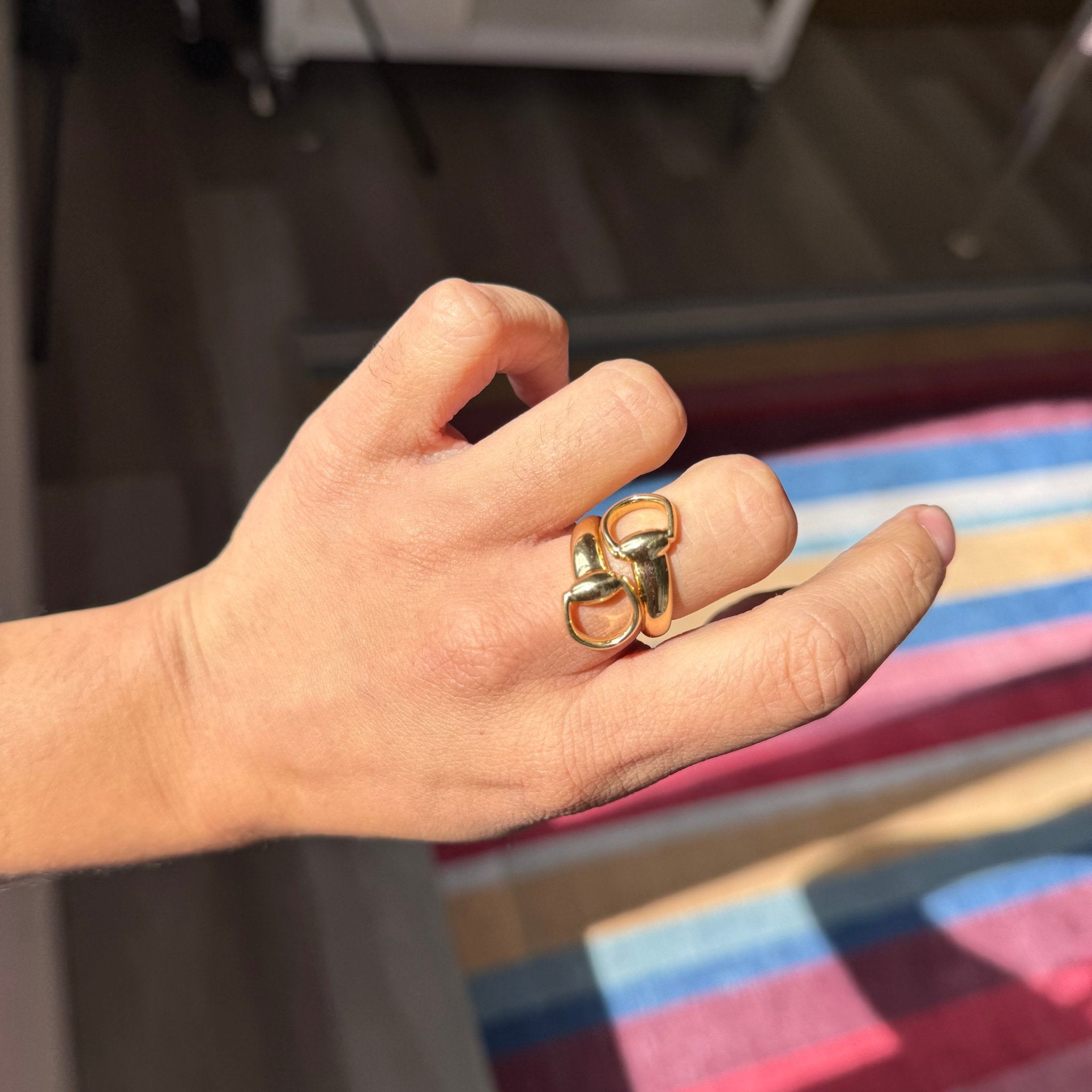 Yellow gold Gucci bypass ring featuring oversized horsebit design, iconic jewelry. Shown on a hand