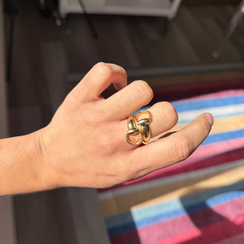 Yellow gold Gucci bypass ring featuring oversized horsebit design, iconic jewelry. Shown on a hand