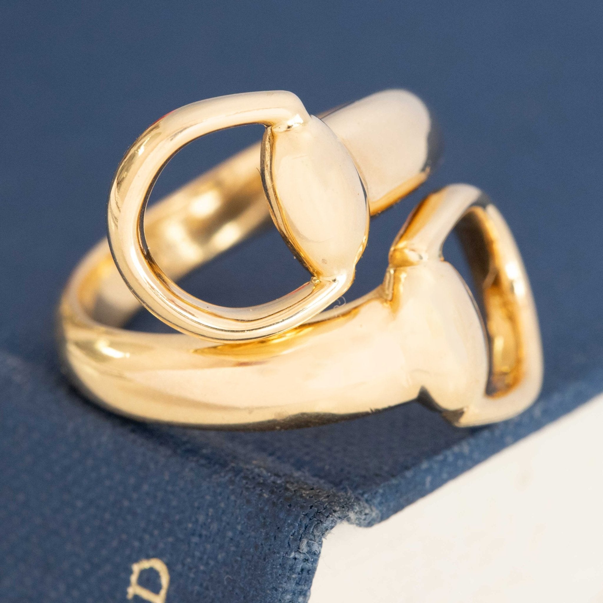 Gucci horsebit motif ring in polished gold, vintage equestrian-inspired bypass design.