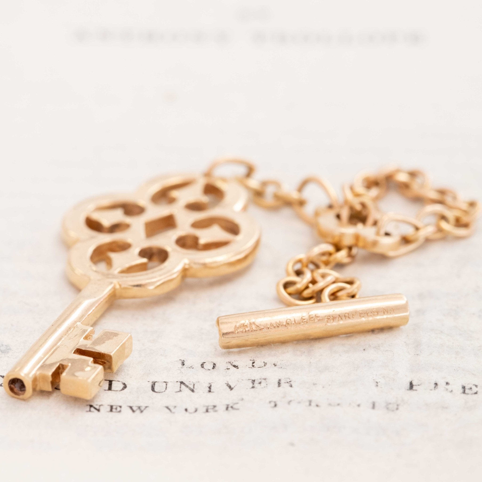Detailed image of vintage Van Cleef & Arpels 18k yellow gold key toggle keychain, a rare collectible VCA design.
Flat lay of Van Cleef & Arpels vintage gold keychain featuring ornate openwork key and short chain toggle clasp.