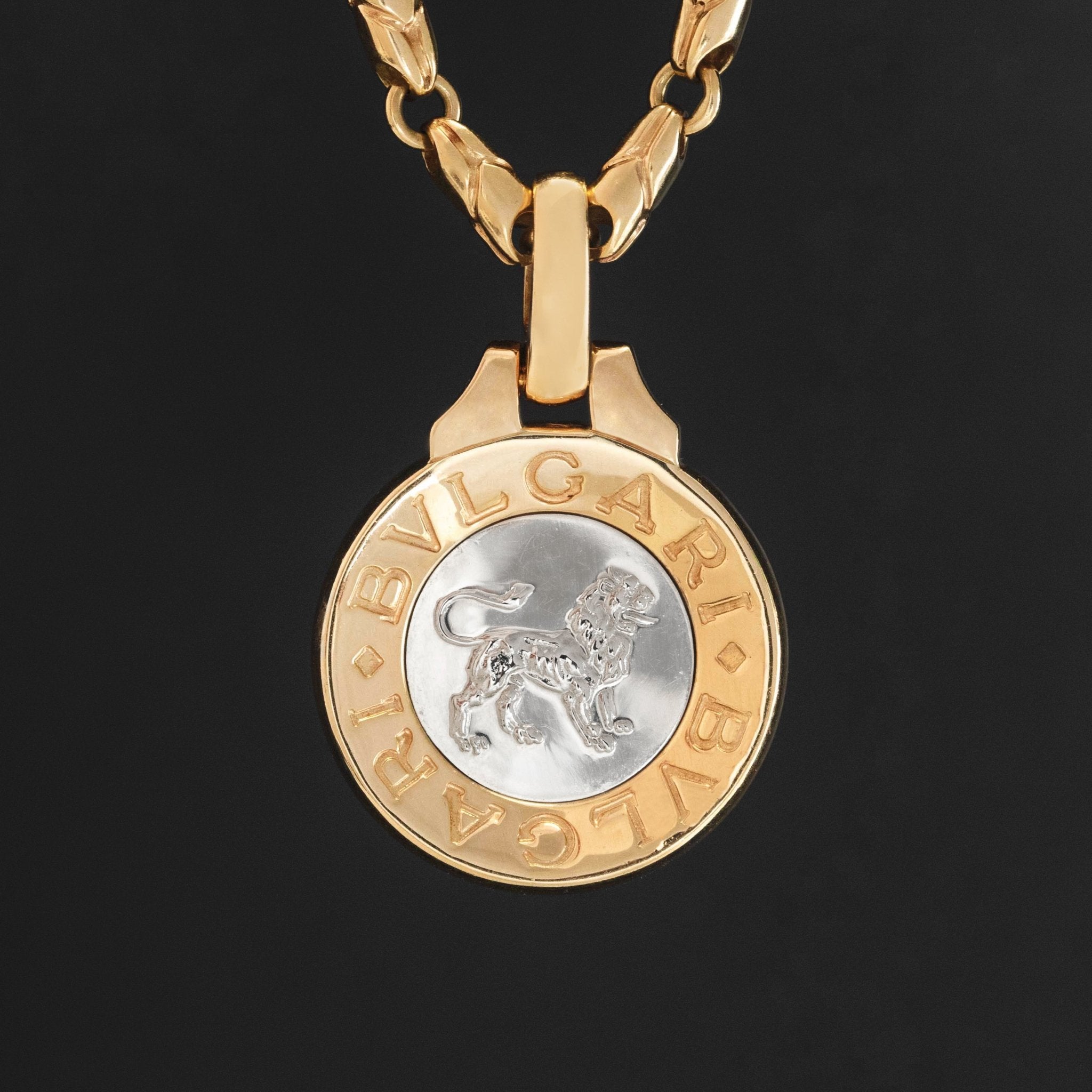 Vintage Bvlgari Leo zodiac pendant crafted in Italy from 18‑karat yellow gold with a contrasting stainless‑steel or white‑gold outer ring. The circular disc is engraved with the BVLGARI logo and features the Libra scales motif at the centre, and it bears hallmarks such as ‘Made in Italy’ and ‘750’.  Measuring roughly 1.23 inches in diameter and weighing about 13 grams, the pendant is numbered on the reverse and hangs from a substantial bail for easy wear as a charm or necklace.