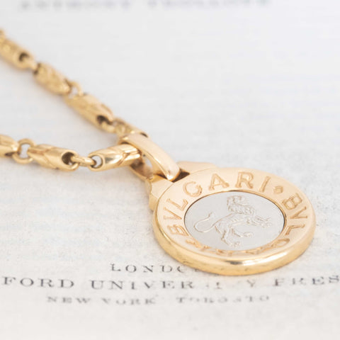 Vintage Bvlgari Leo zodiac pendant crafted in Italy from 18‑karat yellow gold with a contrasting stainless‑steel or white‑gold outer ring. The circular disc is engraved with the BVLGARI logo and features the Libra scales motif at the centre, and it bears hallmarks such as ‘Made in Italy’ and ‘750’.  Measuring roughly 1.23 inches in diameter and weighing about 13 grams, the pendant is numbered on the reverse and hangs from a substantial bail for easy wear as a charm or necklace.  