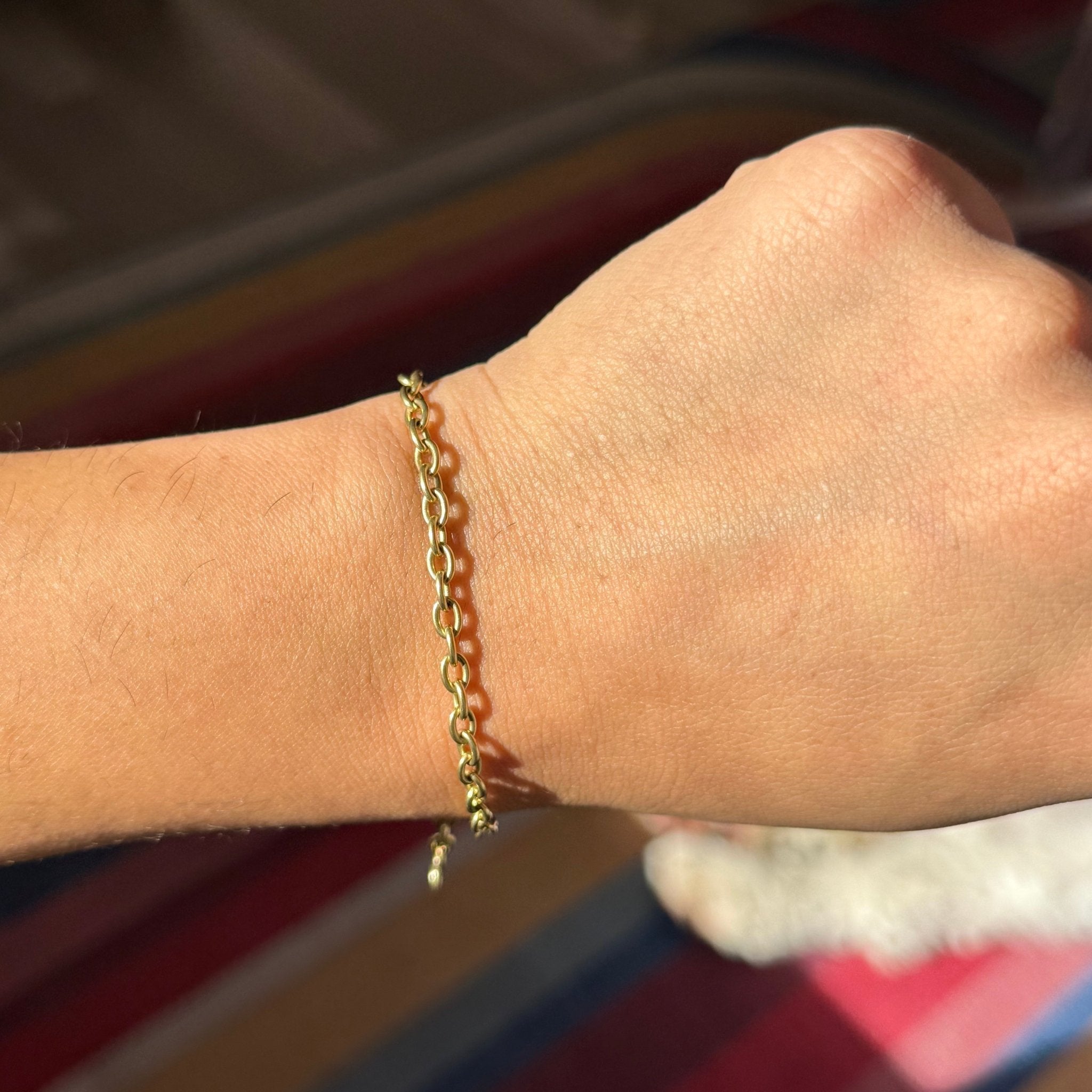 Gold chain bracelet on a wrist with a blurred background