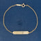 A delicate designer Tiffany & Co. gold chain bracelet with a polished rectangular bar pendant, displayed on a textured blue background.