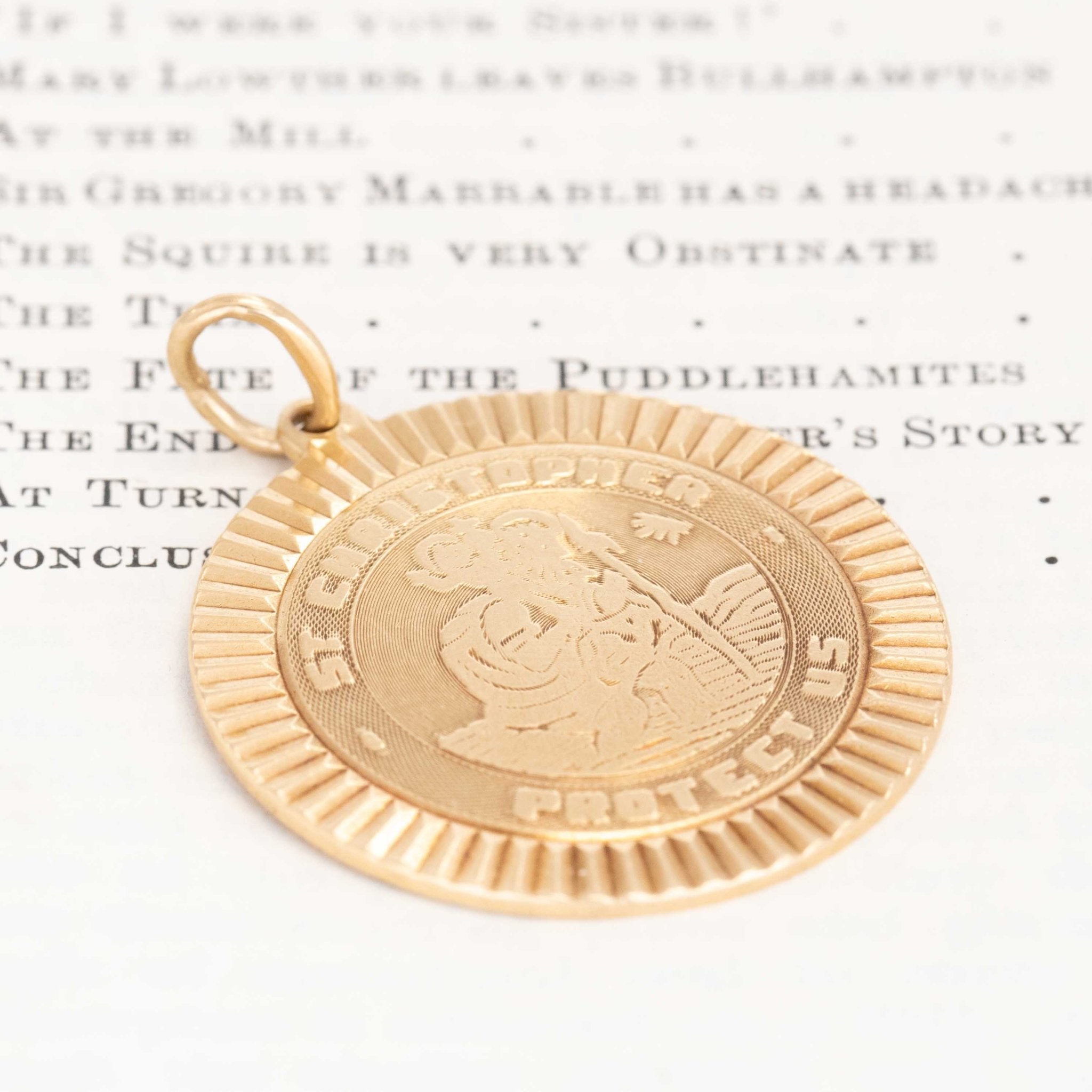 Gold pendant with a face design on a white background with text