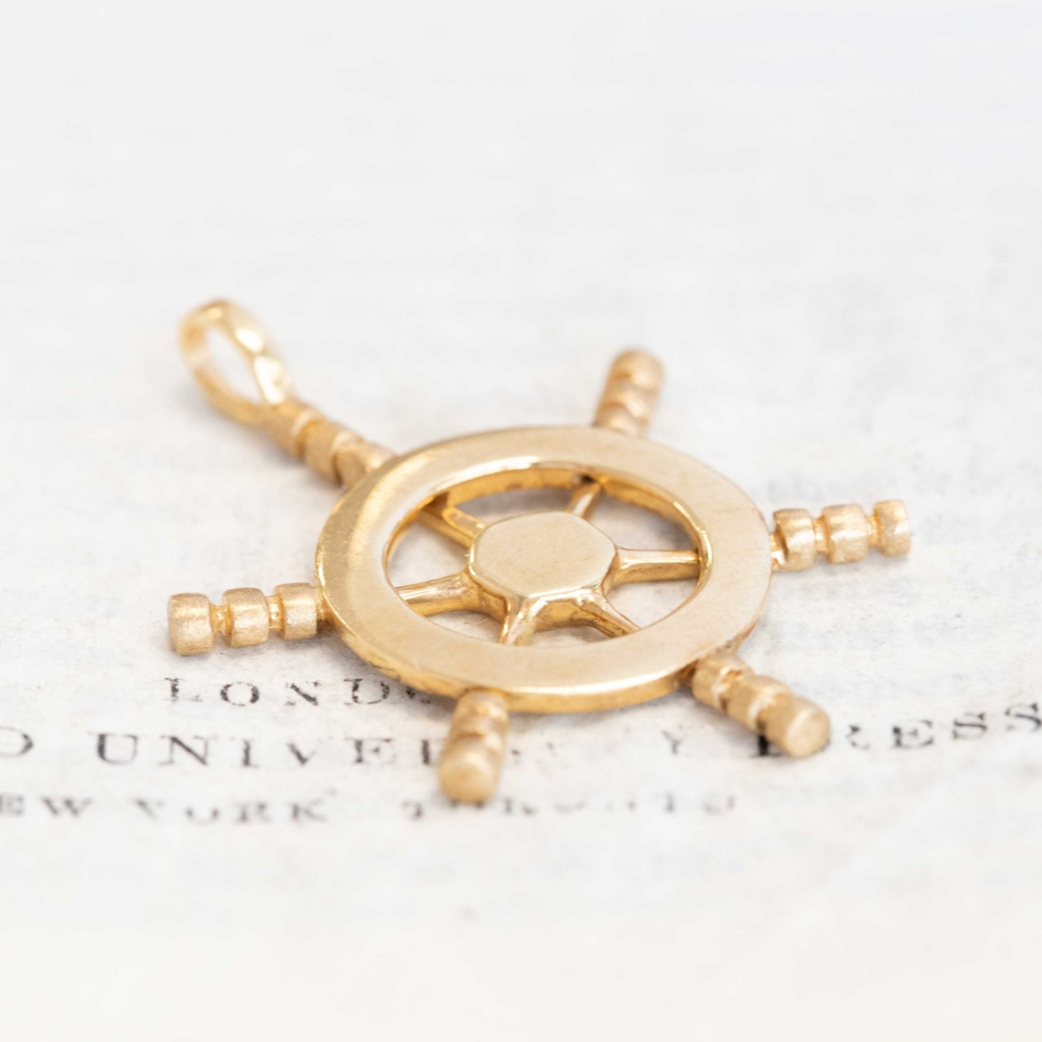 Solid 14k gold ship wheel charm pendant, maritime-inspired collectible jewelry.