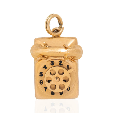A gold vintage telephone pendant charm with a circular rotary dial design and black numbers, shown on a plain white background.