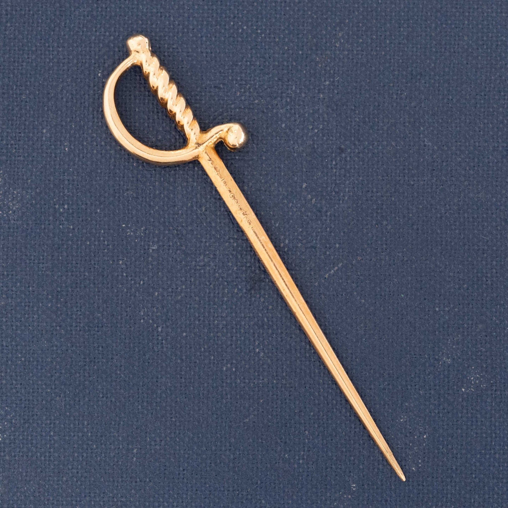 Vintage Cartier 18k yellow gold sword pin with twisted handle and tapered blade, mid-century collectible charm.

Close-up of Cartier vintage gold sword pin showing detailed hilt and slender blade design.