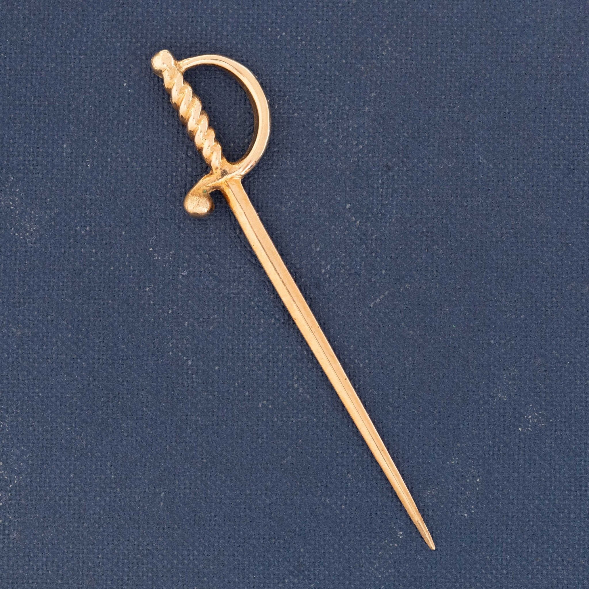 Mid-century Cartier gold sword-shaped charm or lapel pin, 18k yellow gold collectible accessory.

Cartier vintage 18k gold miniature sword pin with sculpted handle and sleek blade.