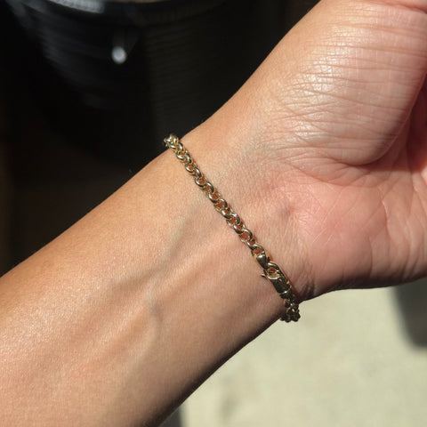 A close-up of a person's wrist wearing a delicate gold chain bracelet.