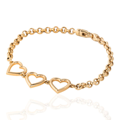 A vintage gold chain bracelet featuring three interlocking open heart charms, displayed on a clean white background with a soft reflection below.