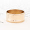 14kt yellow gold wide wedding band with a concave center and milled edges.