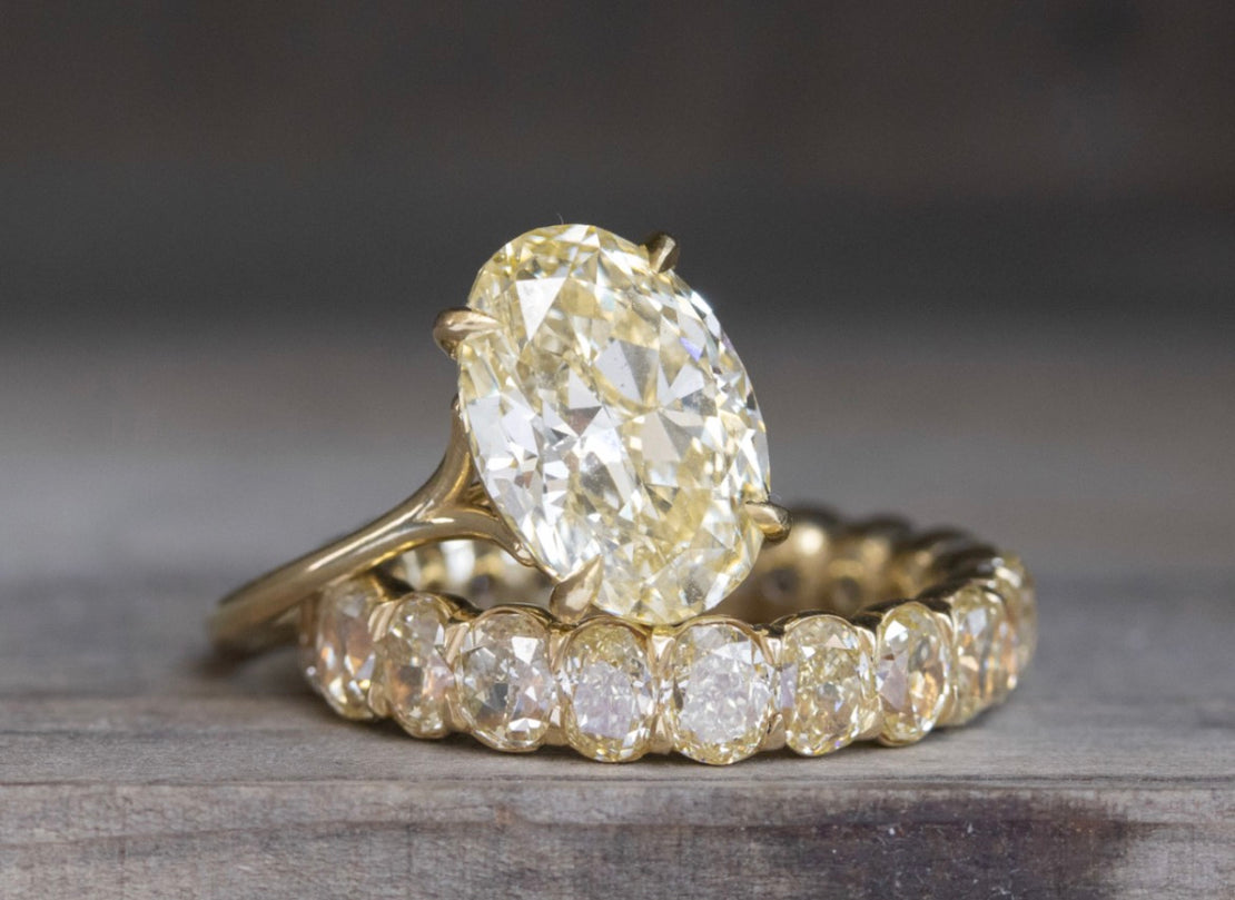 yellow oval solitaire engagement ring on top of a yellow oval diamond eternity wedding ring